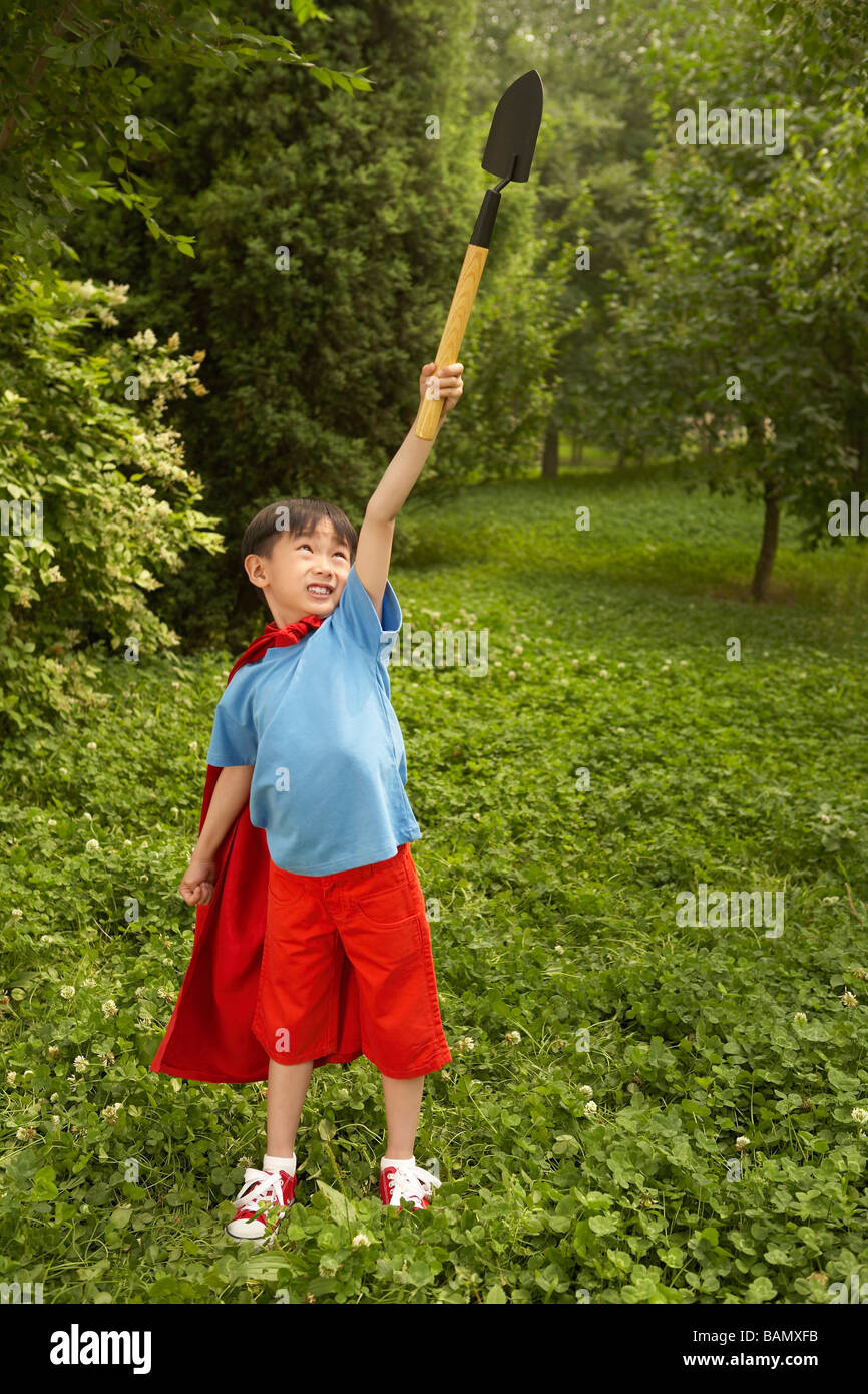 Boy Standing In Garden Holding Spade dans l'air Banque D'Images