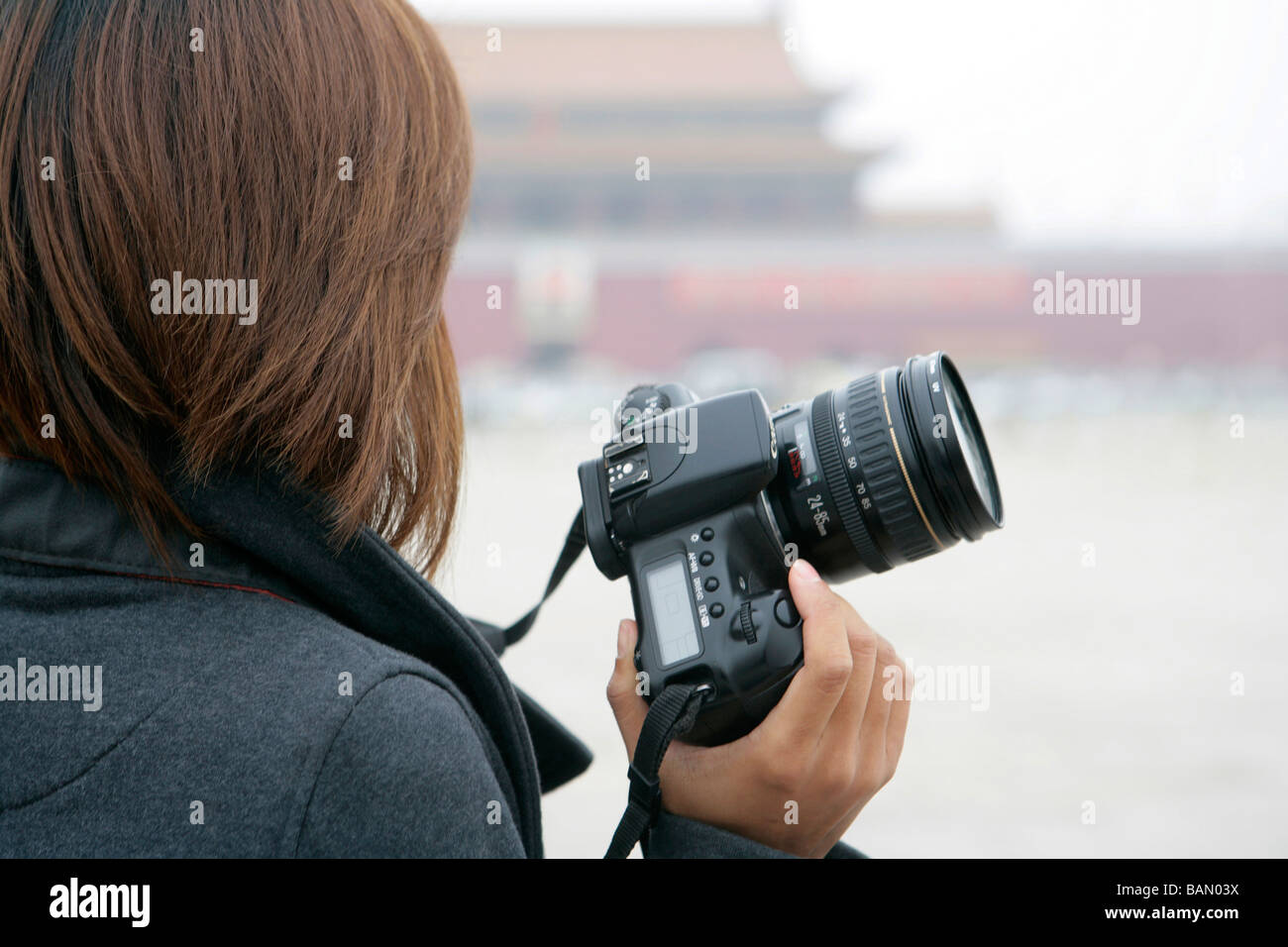 Young woman holding camera donne à la place Tiananmen, Pékin, Chine Banque D'Images