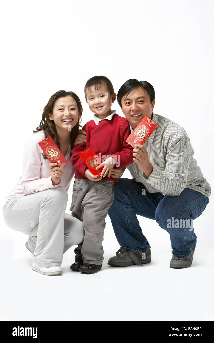 Portrait d'une jeune famille de l'enfant unique holding enveloppes rouges pour le Nouvel An chinois Banque D'Images