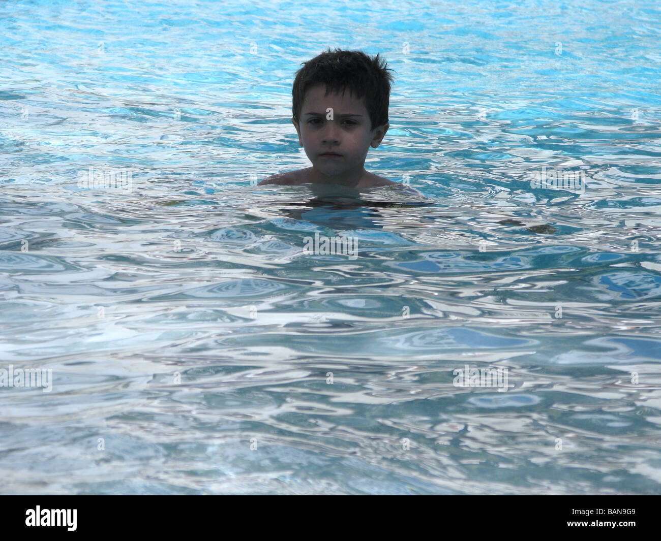 Un jeune garçon dans l'eau des piscines Banque D'Images