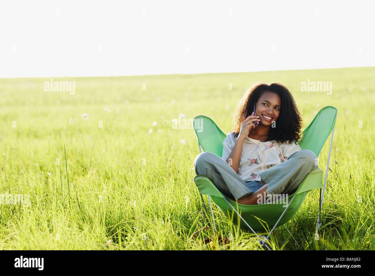 African woman using cell phone in meadow Banque D'Images