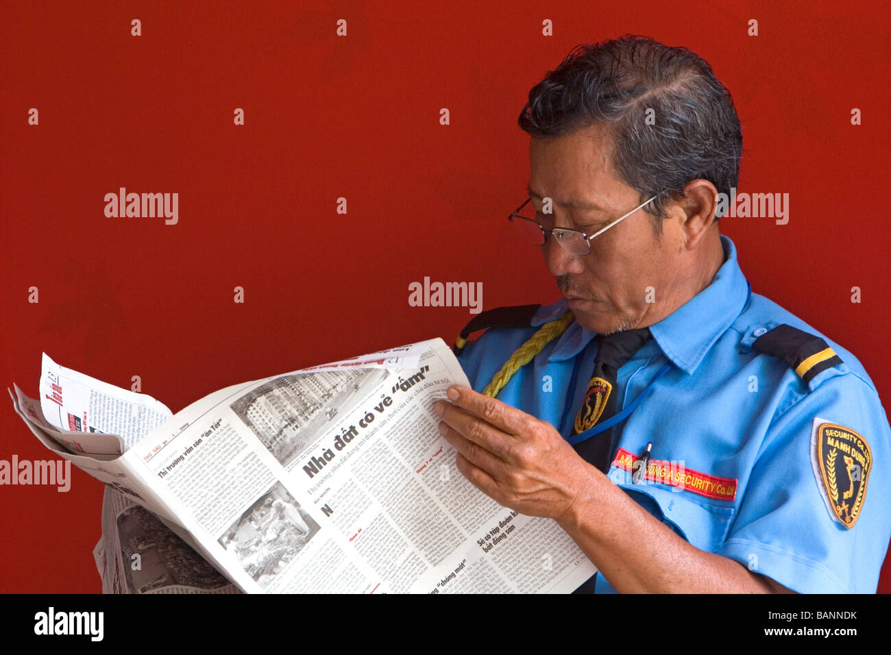 Garde de sécurité vietnamiennes lire un journal à Ho Chi Minh City Vietnam Banque D'Images