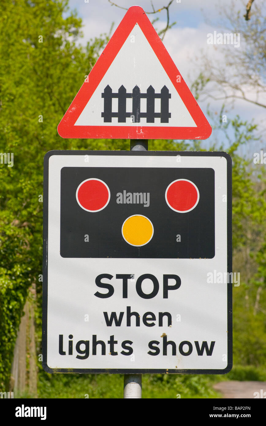 La gare ferroviaire d'arrêt du passage à niveau lorsque les lumières Show UK Road traffic Sign signe panneaux roadsign Banque D'Images