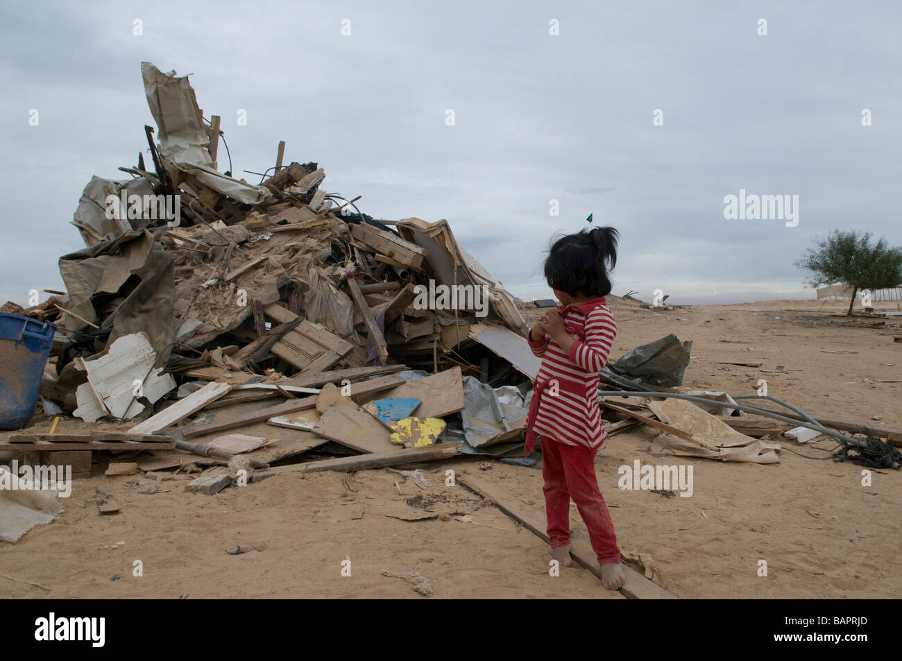 Fille de bédouins au milieu stand ruine de démoli la maison rasée par les autorités israéliennes à Abdallah Al Atrash village bédouin non reconnu dans le désert du Néguev, Israël Banque D'Images