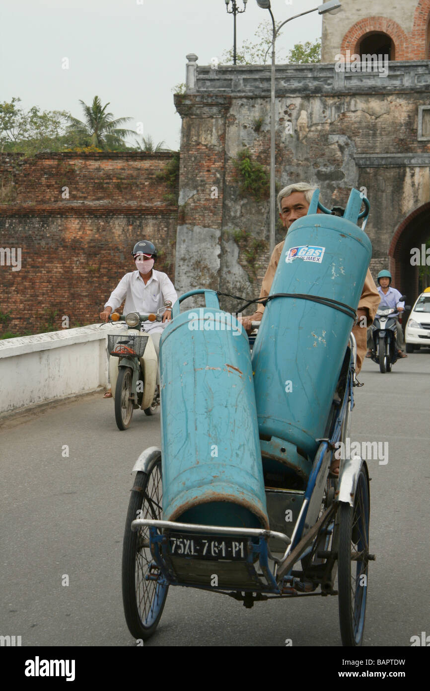 Un homme monte un cyclo à Hanoi, Vietnam avec deux grandes bouteilles de gaz à bord Banque D'Images