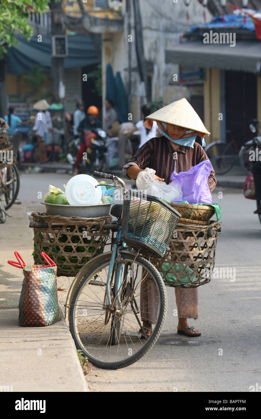 Une femme équilibre sa fruit sur son vélo à Hoi An, Vietnam Banque D'Images