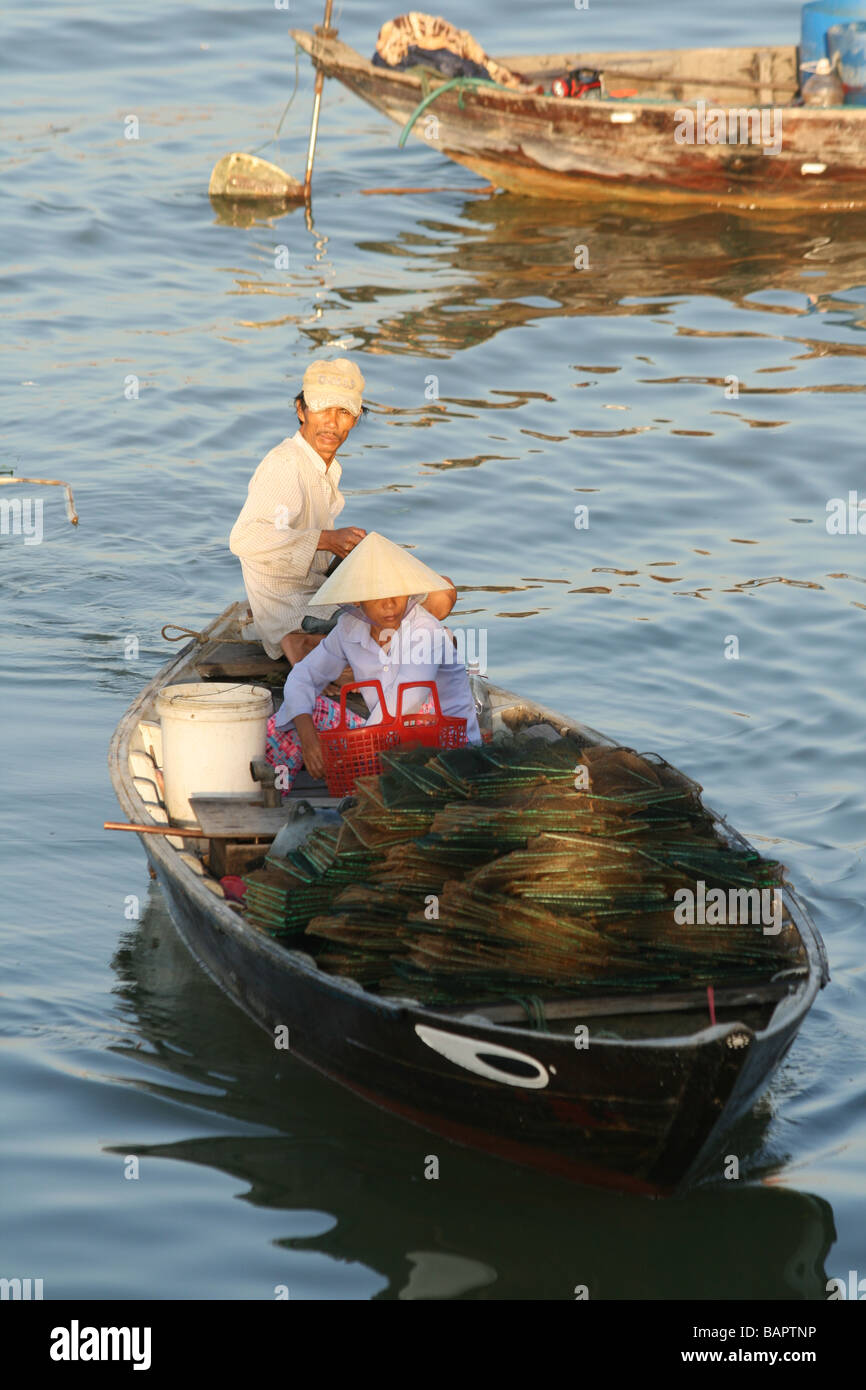 Un homme et une femme sur un bateau de pêche arrivent sur le marché pour vendre leurs prises à Hoi An, Vietnam Banque D'Images