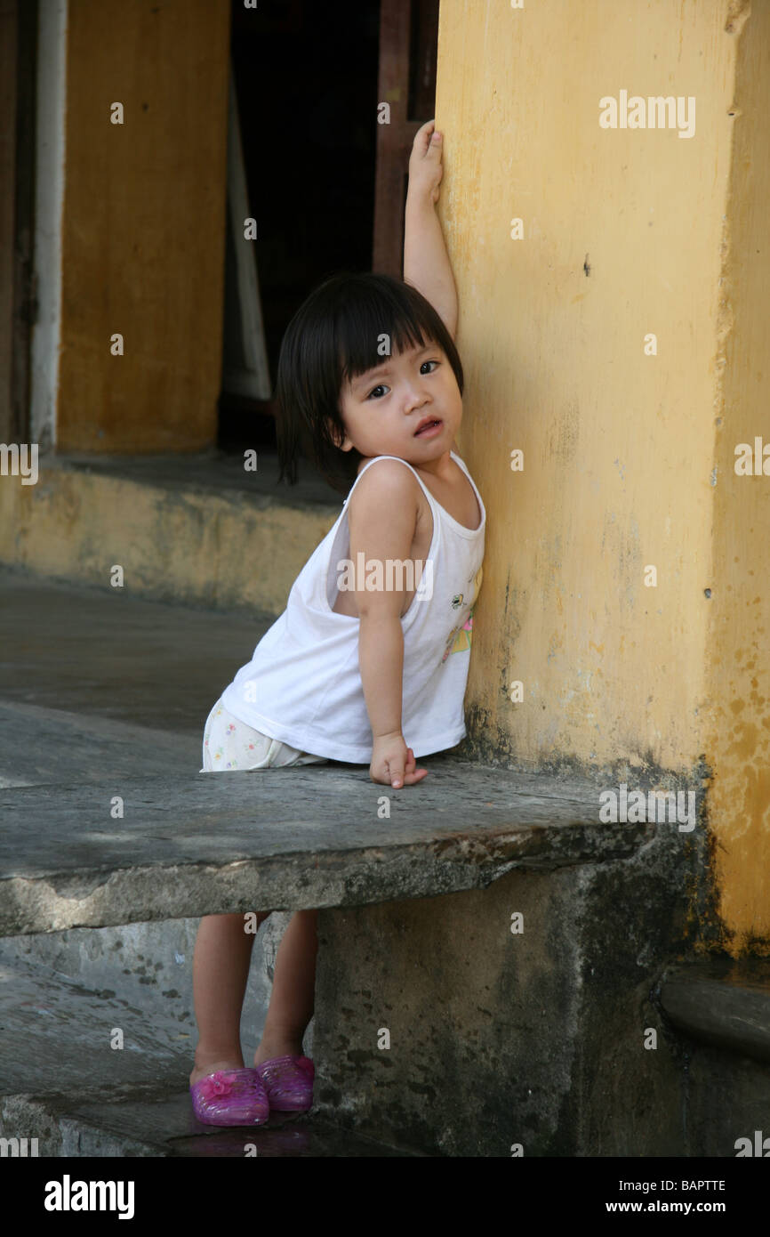 Une jeune fille s'appuie contre le mur de sa maison à Hoi An, Vietnam Banque D'Images