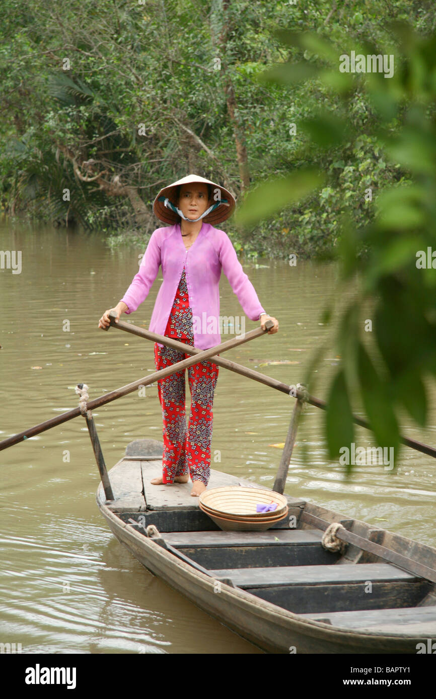 Les lignes d'une femme un bateau en bois le long d'une des autoroutes de l'eau du delta du Mékong au Vietnam Banque D'Images