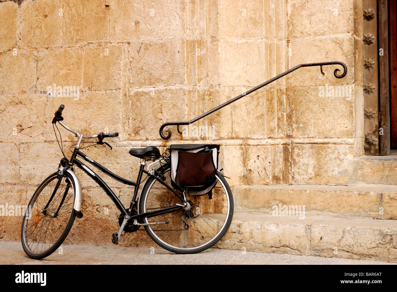 Vieux vélo appuyé contre un mur de l'église en pierre Banque D'Images