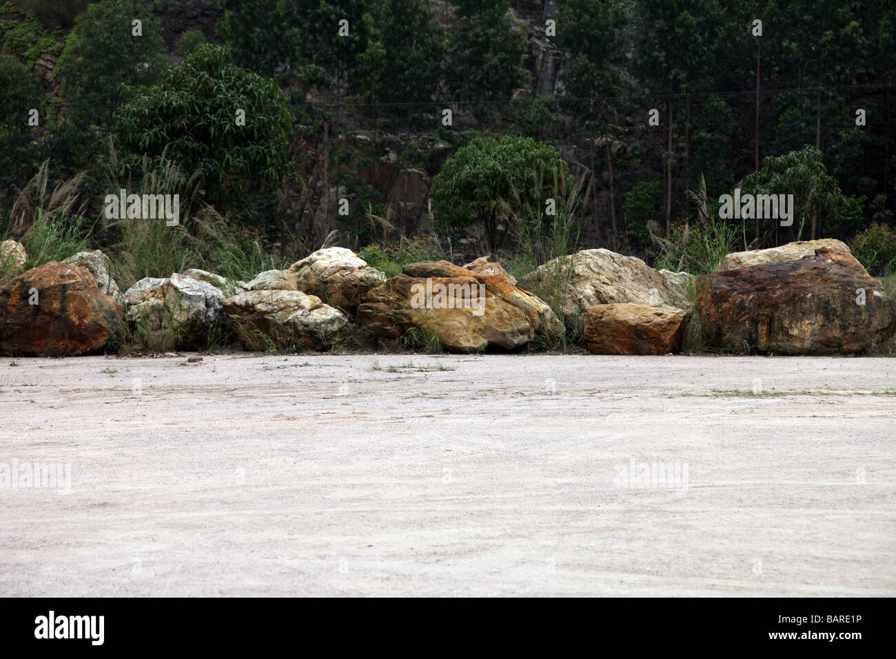 Une gamme de gros rochers ou des pierres sur l'extrémité d'une cour le long d'une forêt. C'est un parking en plein milieu de la Chine. Pauvres vide Banque D'Images