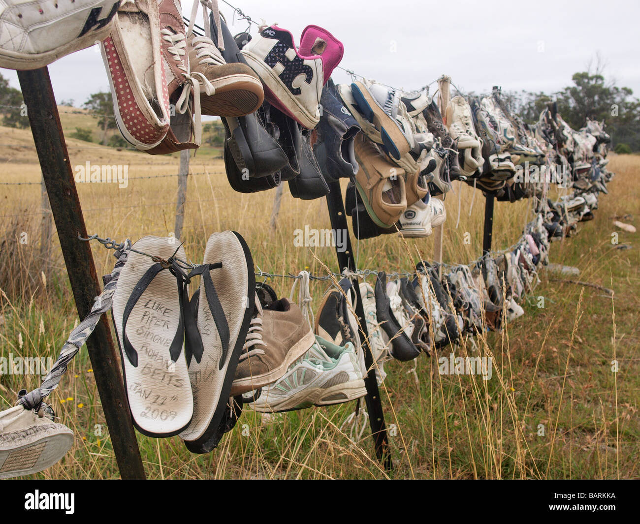 Formateurs perdus et abandonnés, des tongs et des chaussures accrochées sur barbelés Tasmanie Australie Banque D'Images