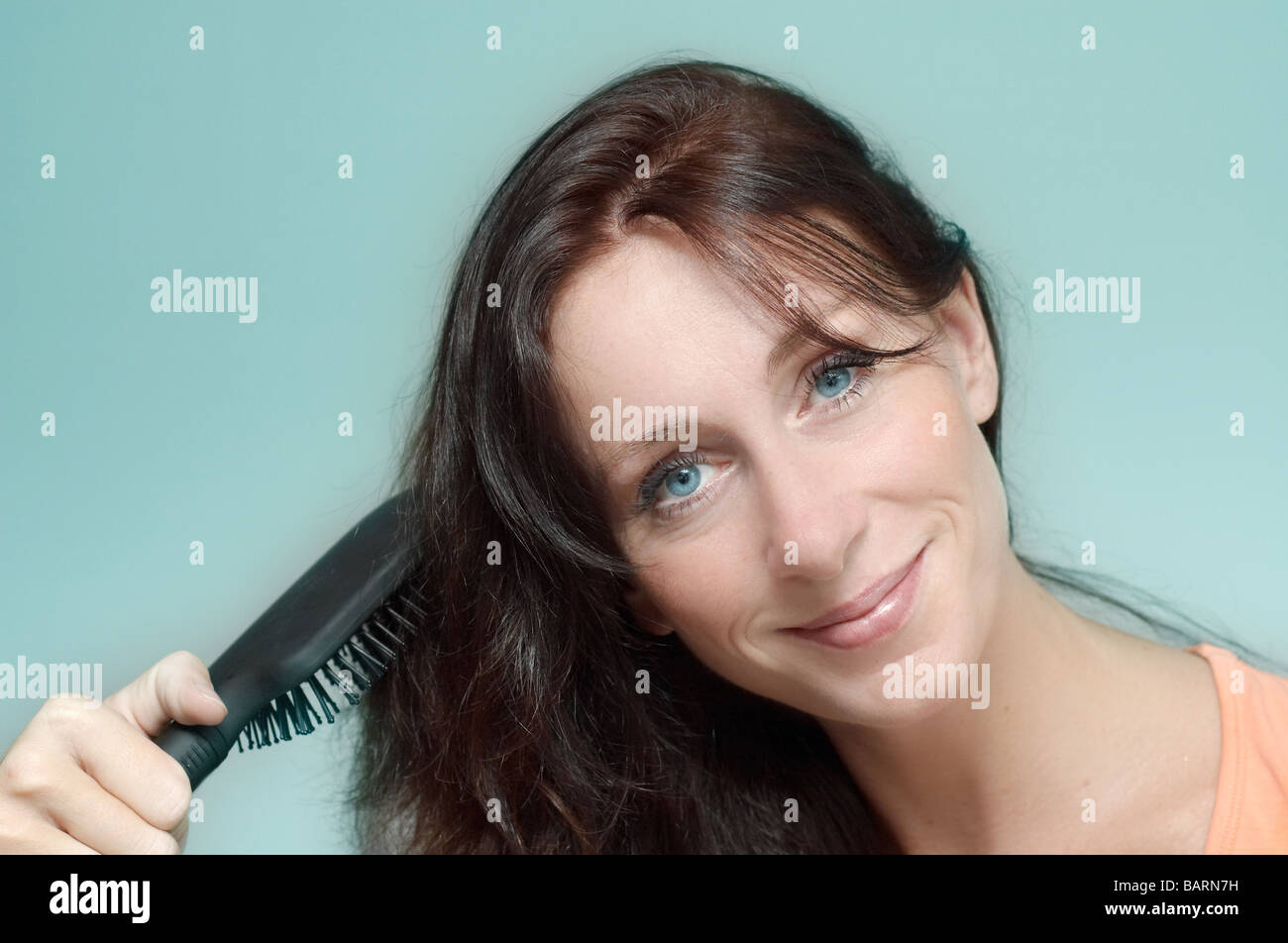 Smiling woman doing her hair Banque D'Images