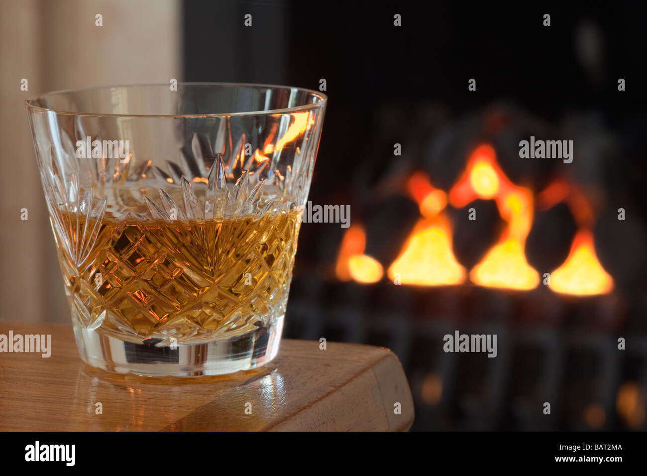 Petit Verre de single malt scotch whisky dans un verre à whisky en cristal sur une table par une cheminée Angleterre Royaume-uni Grande-Bretagne Banque D'Images