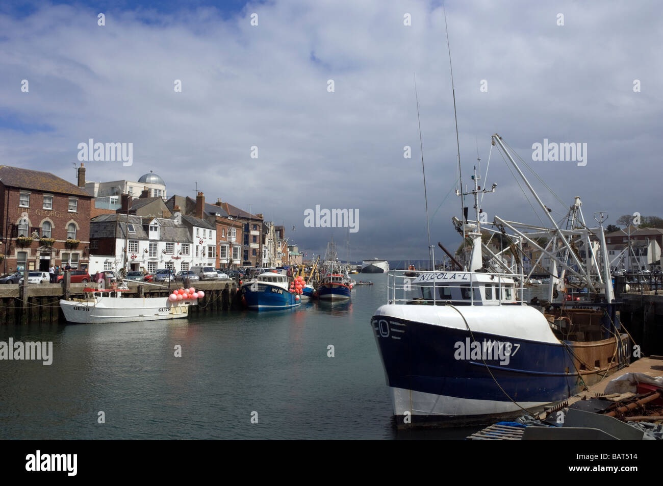 Les nuages de tempête rouler dans plus de la flotte de pêche amarré au port de Weymouth, dans le Dorset, Angleterre. Banque D'Images
