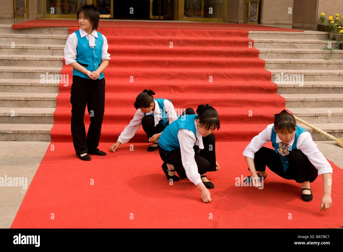 LISHI, CHINE - JUIN 2006 : le personnel de l'hôtel Lishi International nettoie le tapis rouge avant l'arrivée d'une délégation. Lishi se trouve dans la province du Shanxi, une des provinces les plus polluées de Chine. Banque D'Images