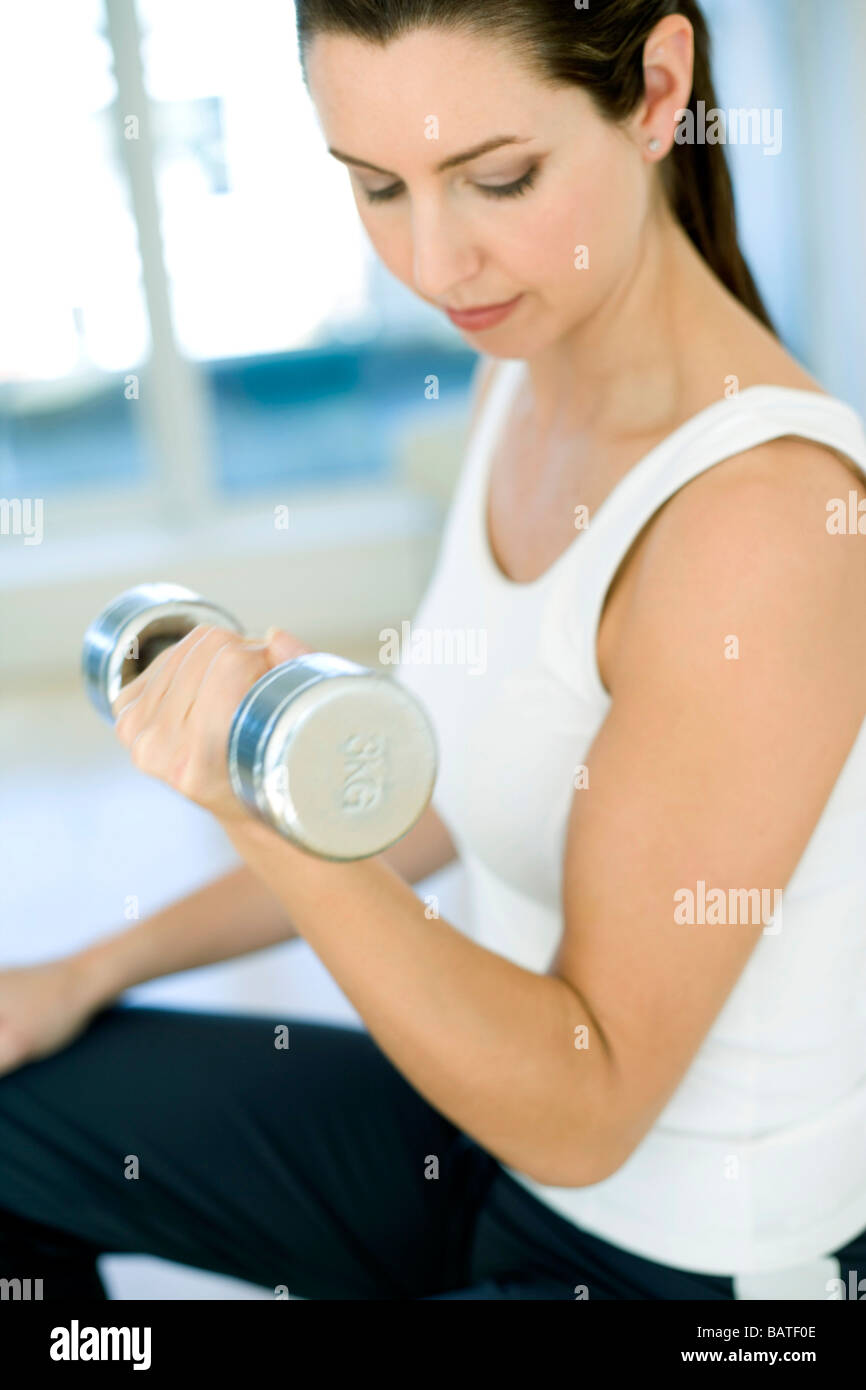 L'haltérophilie. Woman lifting dumbbells. Cet exercice est appelé un biceps curl,et est l'exercice de ses biceps brachii muscles. Banque D'Images