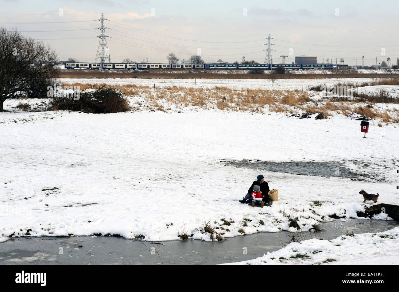 Femme avec enfant assis dans la neige sur les marais de Walthamstow Lea Valley London Banque D'Images