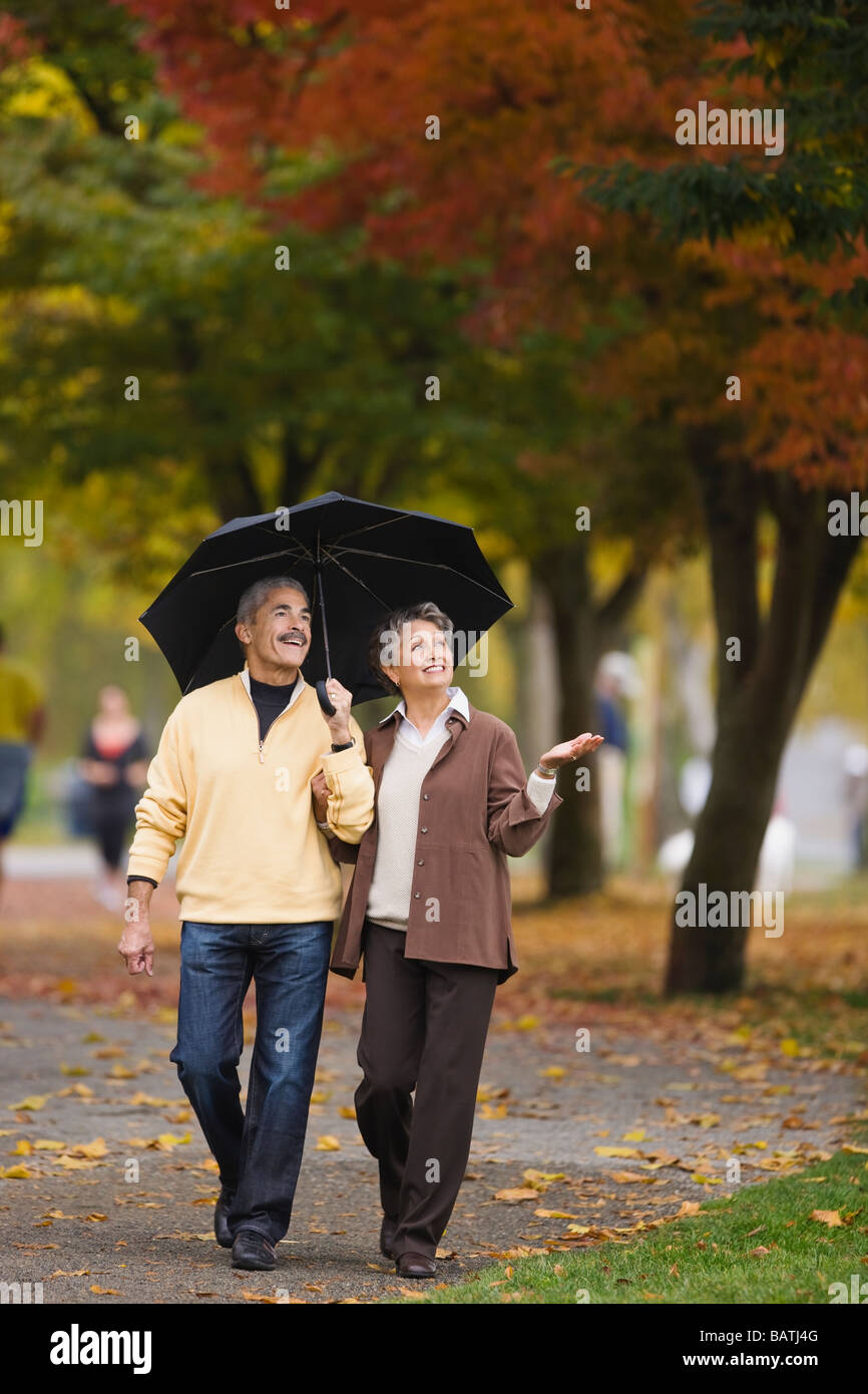 African couple walking avec parapluie en automne Banque D'Images