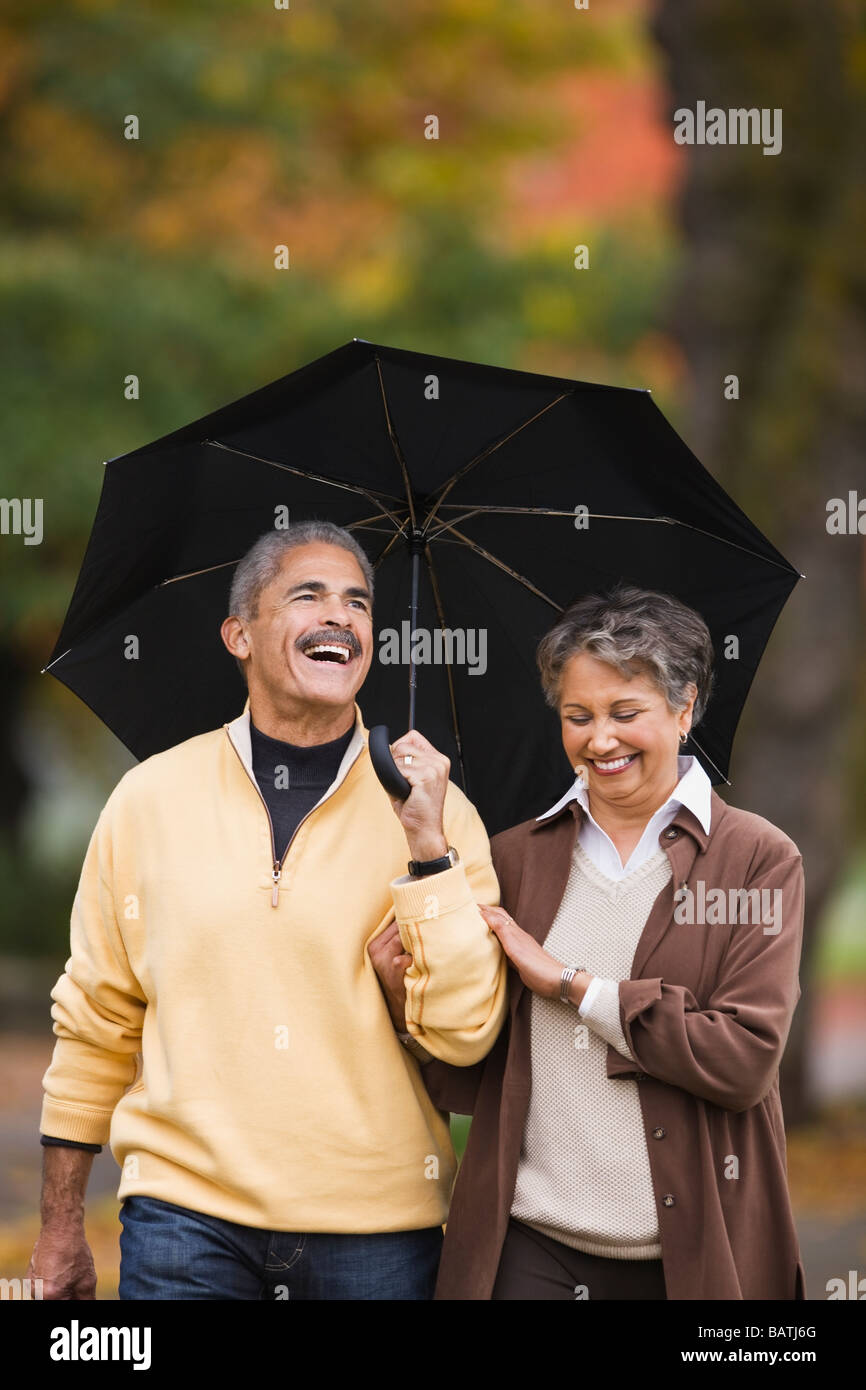African couple walking avec parapluie en automne Banque D'Images