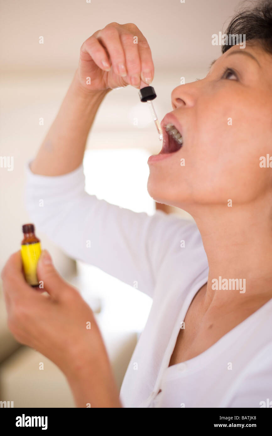 Rescue Remedy. Femme à l'aide d'une pipette pour prendre un extrait connu sous le nom de Bach Rescue Remedy. Banque D'Images