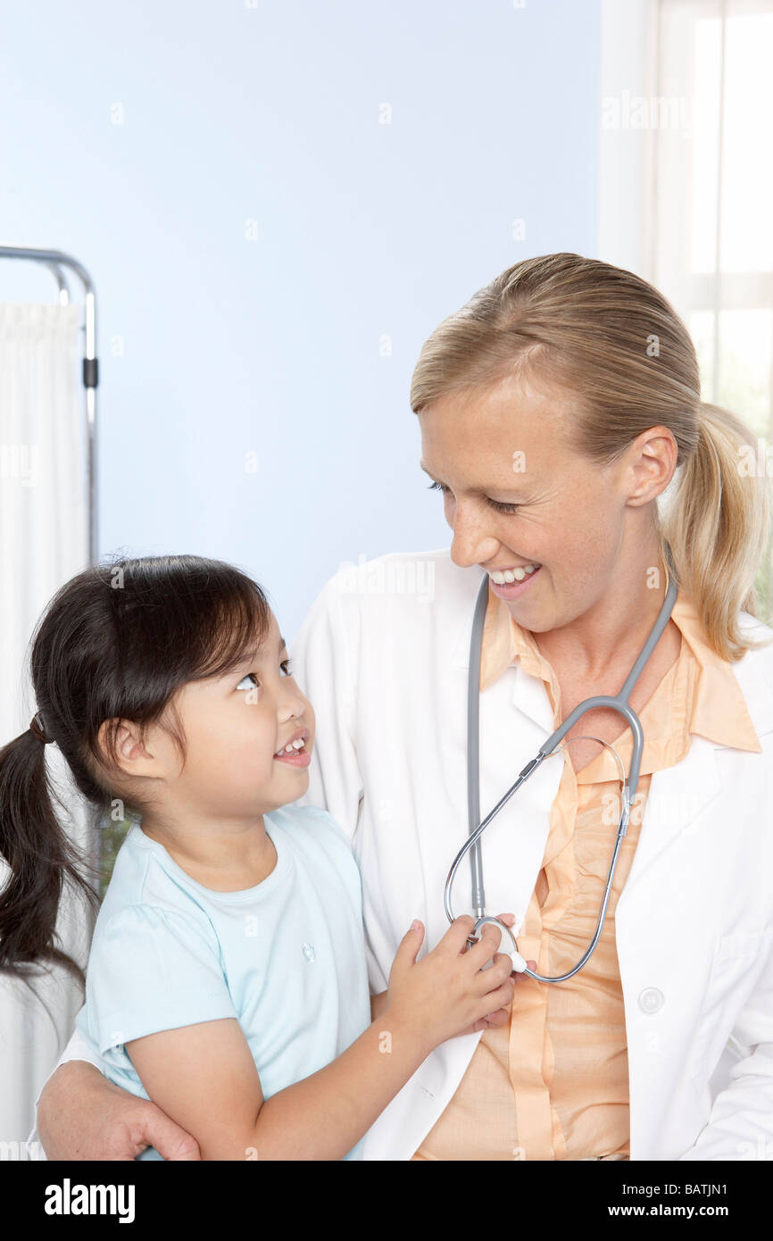 Médecin et l'enfant. Petite fille de cinq ans et son médecin de famille jouant avec un stéthoscope. Banque D'Images