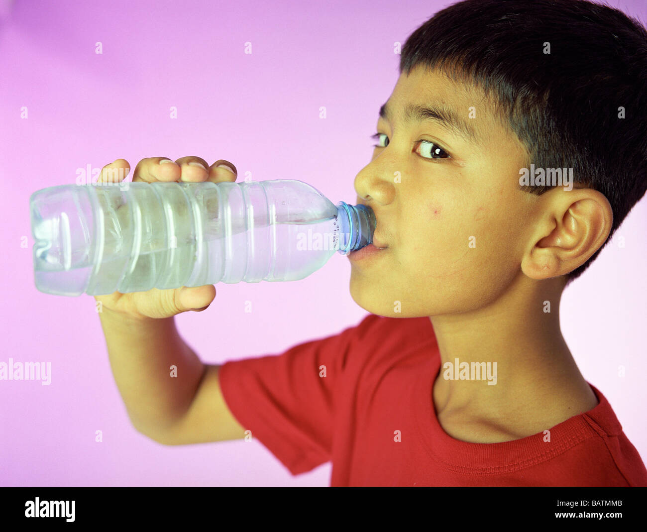 L'eau potable. Jeune garçon de 9 ans boire d'une bouteille d'eau. Banque D'Images