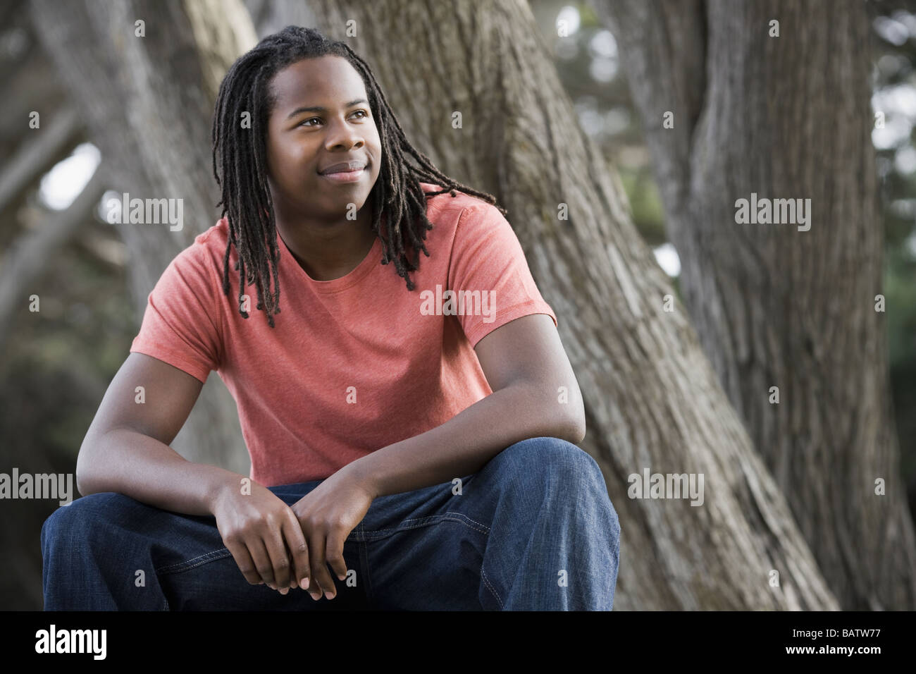 Teenage boy (16-17) avec des dreadlocks, sitting in park Banque D'Images