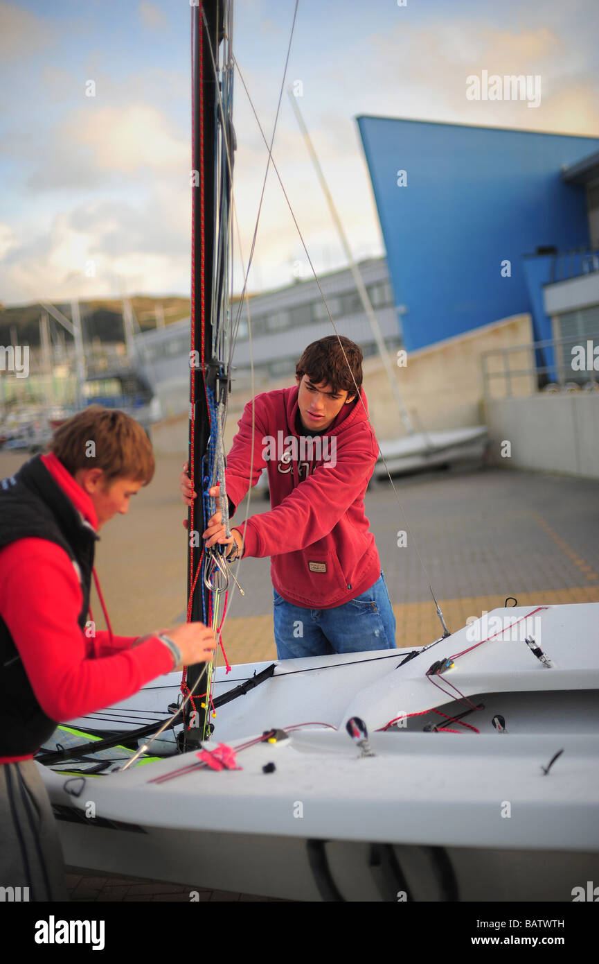 Deux jeunes hommes se préparent à sortir la voile à l'académie à Weymouth et Portland, dans le Dorset. Banque D'Images