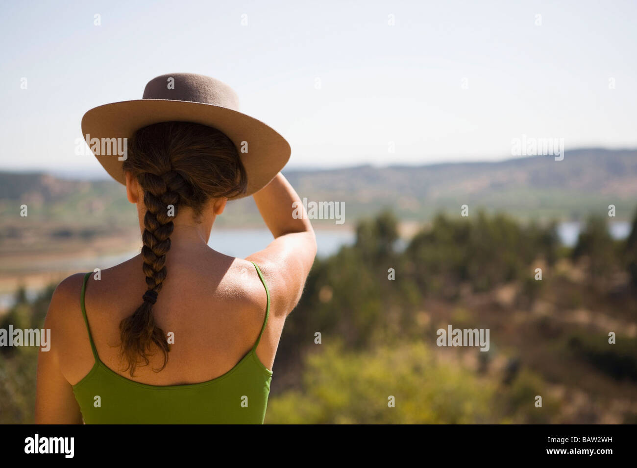 Hispanic woman in hat viewing remote landscape Banque D'Images