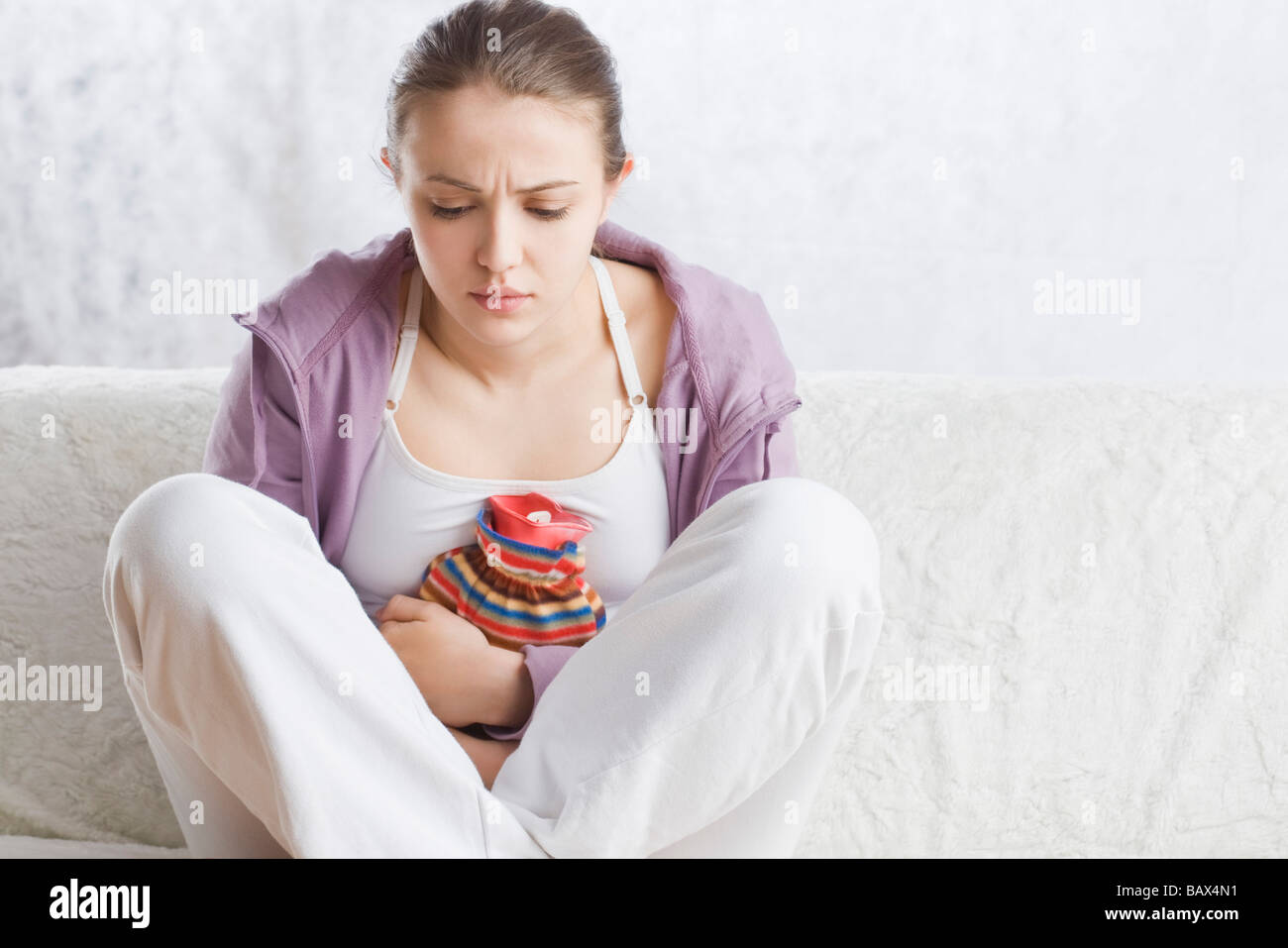 Jeune femme avec bouteille à eau chaude sur l'estomac Banque D'Images