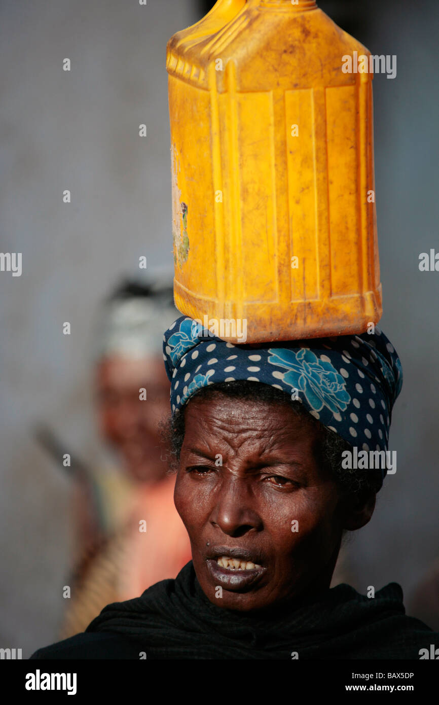 Femme portant un récipient de l'eau jaune sur sa tête en vieille Harar en Ethiopie Banque D'Images