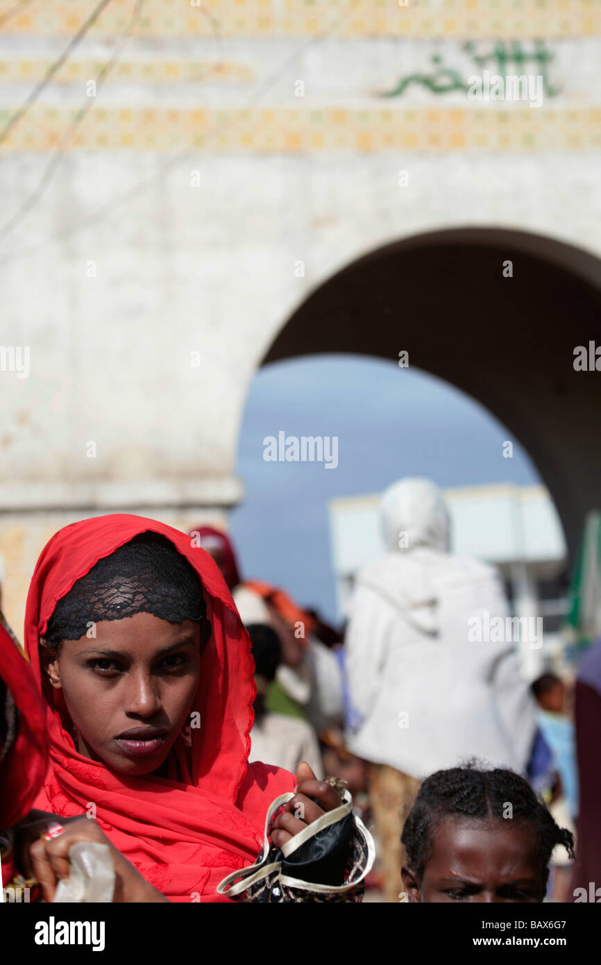 Jolie femme dans un foulard rouge en face de Harar Gate dans le marché de Harar vieux chrétiens Ethiopie Banque D'Images