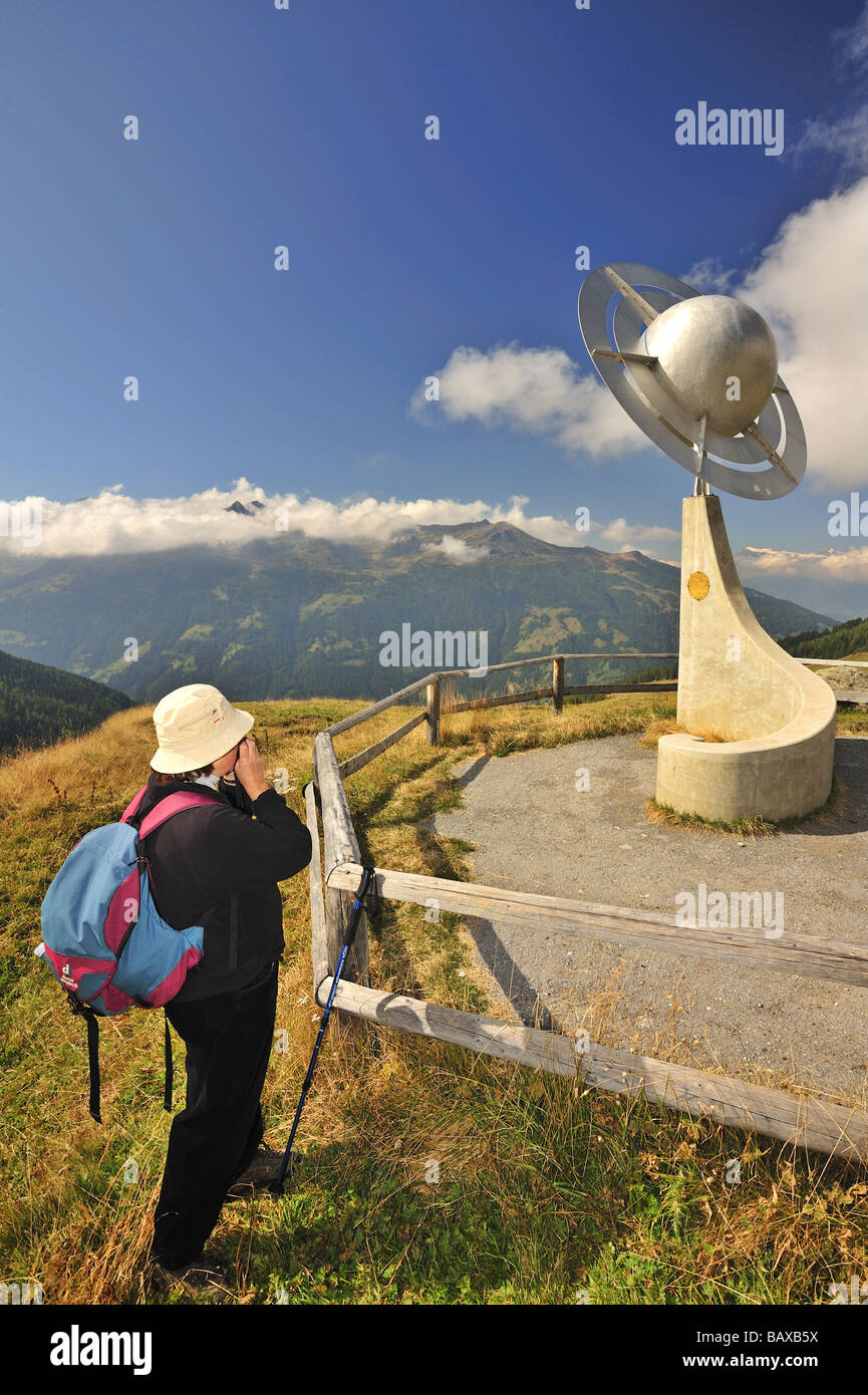 Une femme hiker photographies une sculpture représentant les planètes Saturne le sentier (Sentier des planetes) dans les Alpes suisses. Banque D'Images