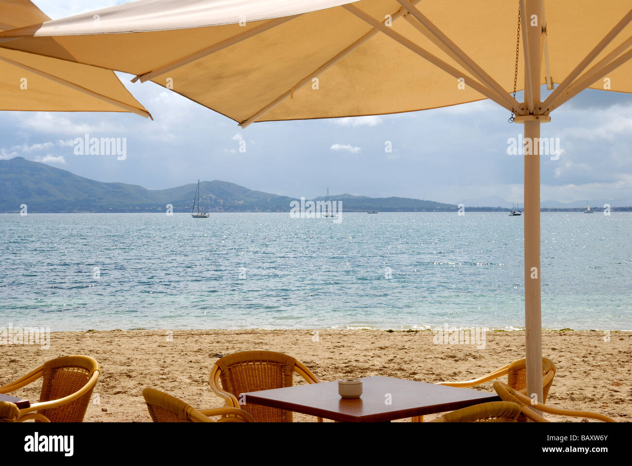 Parasols sur tables en bois avec des chaises en osier, plage, et la mer en arrière-plan Banque D'Images