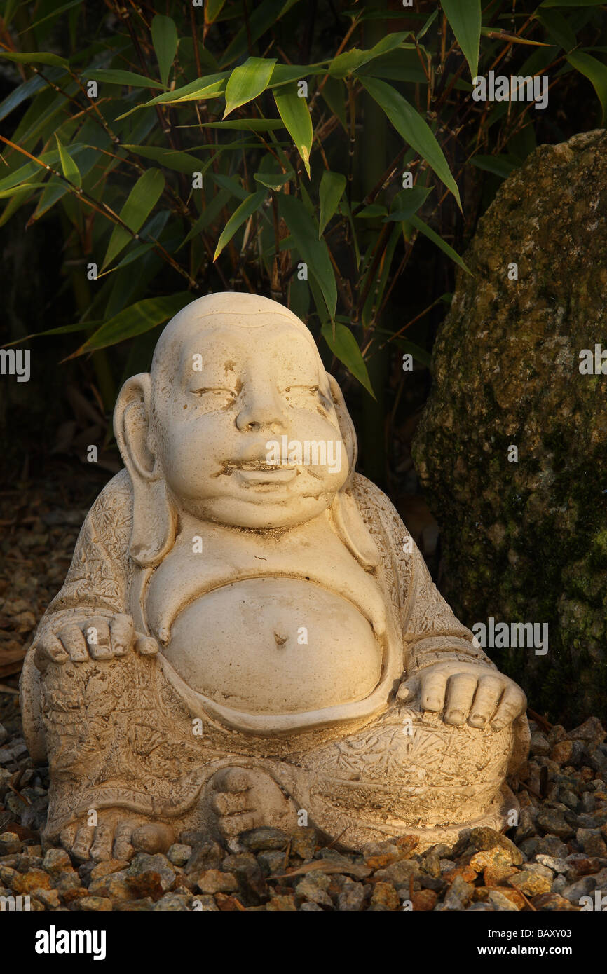 Une statue de Bouddha dans un jardin de gravier derrière un rocher et bambou d'un côté l'éclairage pommelé Limousin France Banque D'Images