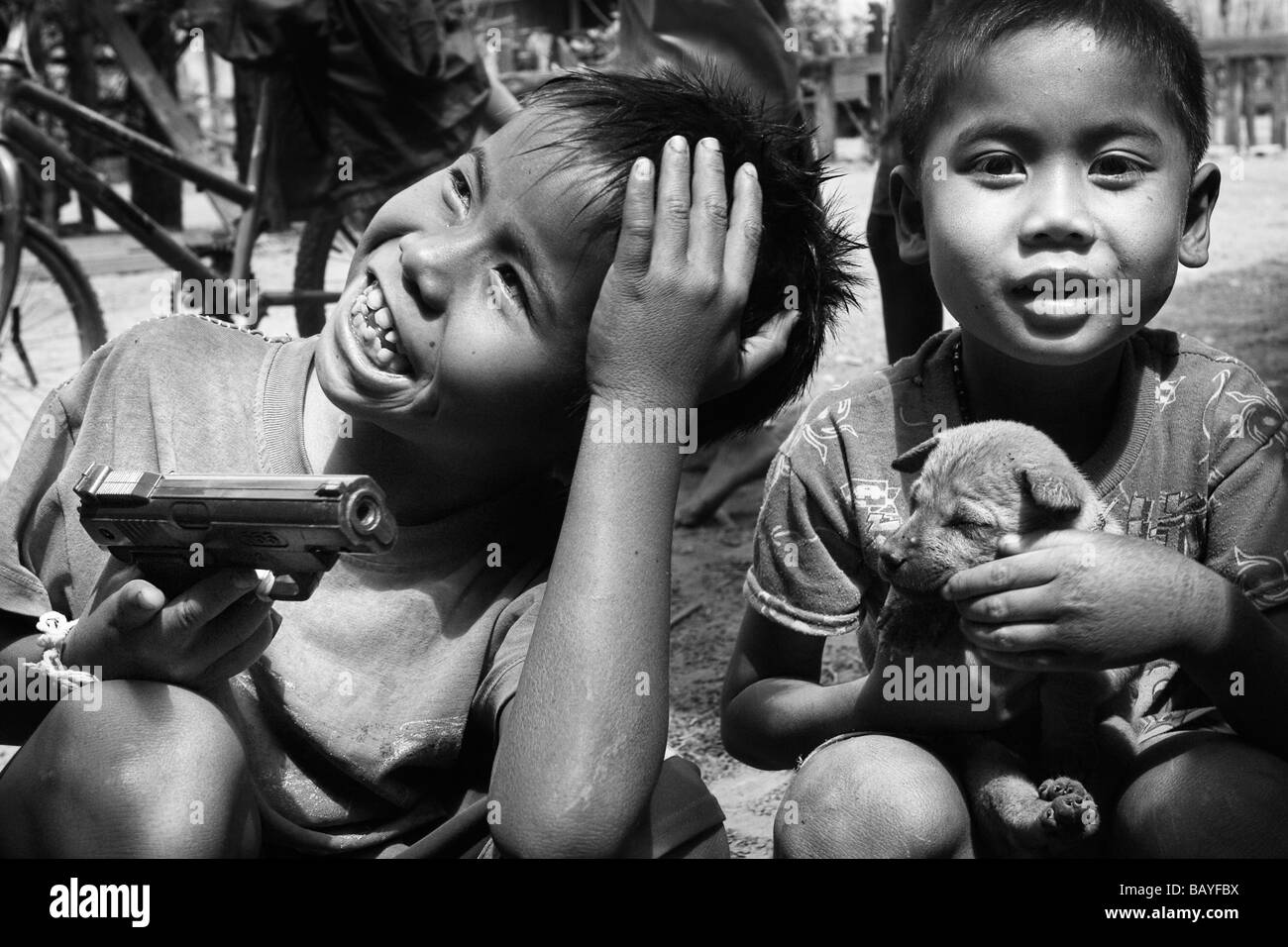 Les garçons jouent avec un chiot et d'un pistolet jouet à Naku Village, Phu Hin Bun zone protégée nationale, République démocratique populaire lao. Banque D'Images