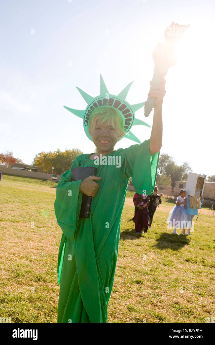 Fille de l'âge de l'école élémentaire habillés en costume halloween Statue de la liberté, la tenue à la lumière du soleil de la flamme Banque D'Images
