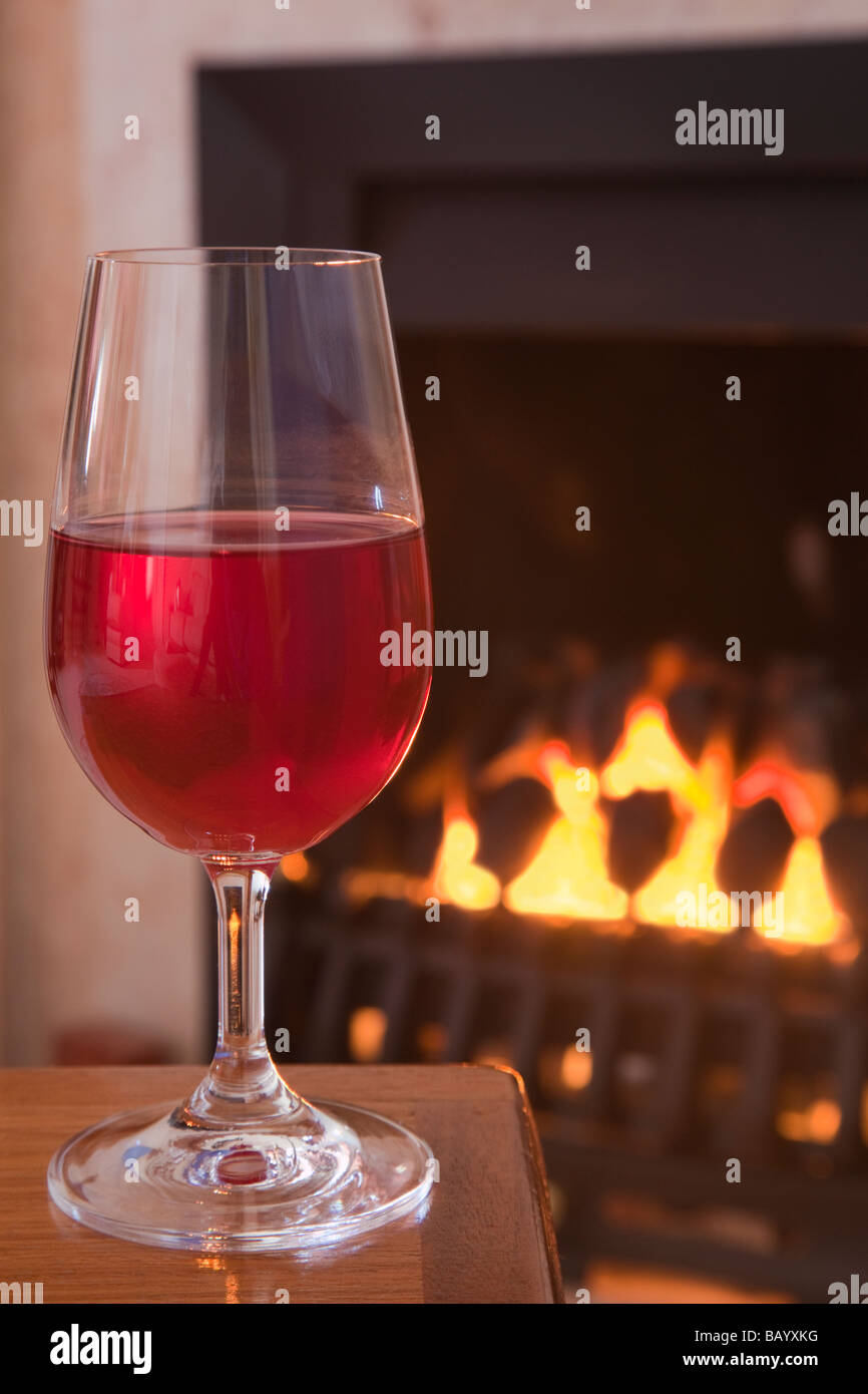 Verre de vin rouge sur une table par un feu de charbon gaz Angleterre Grande-bretagne UK Banque D'Images