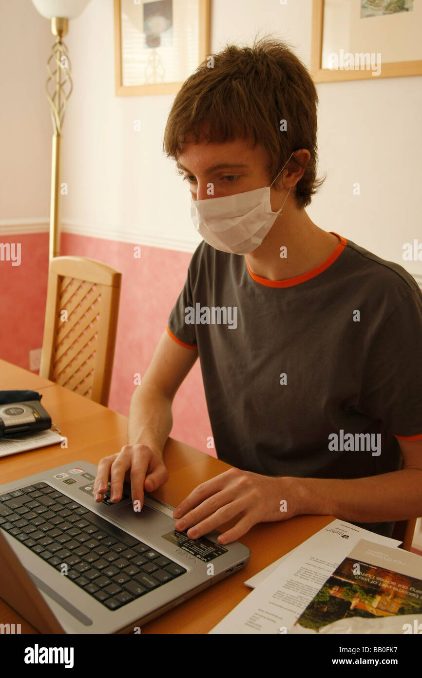 Jeune homme travaillant sur un ordinateur portable portant un masque de visage Banque D'Images