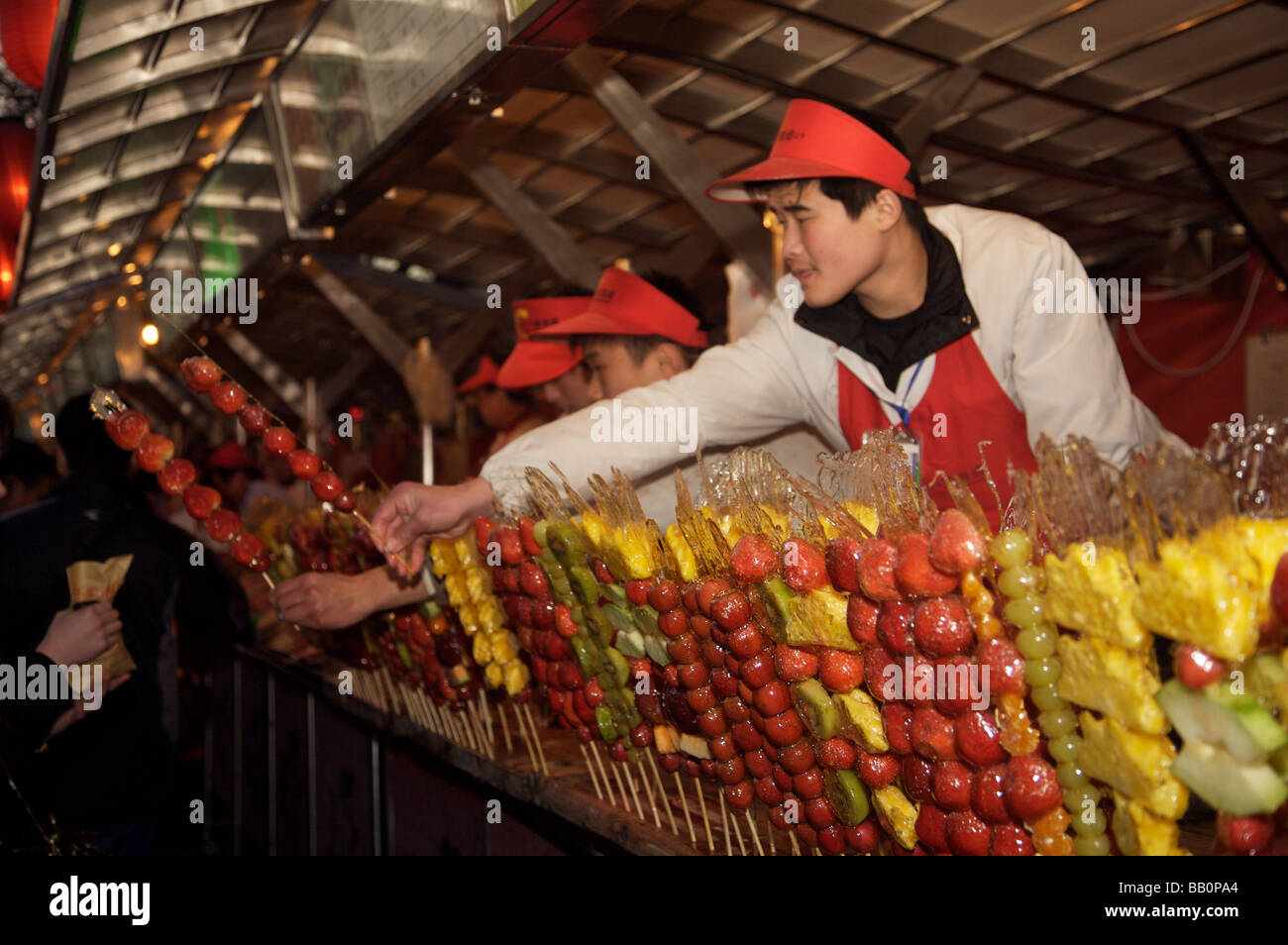 Man selling fruits confits bâtons à un décrochage du marché de nuit à Beijing Banque D'Images