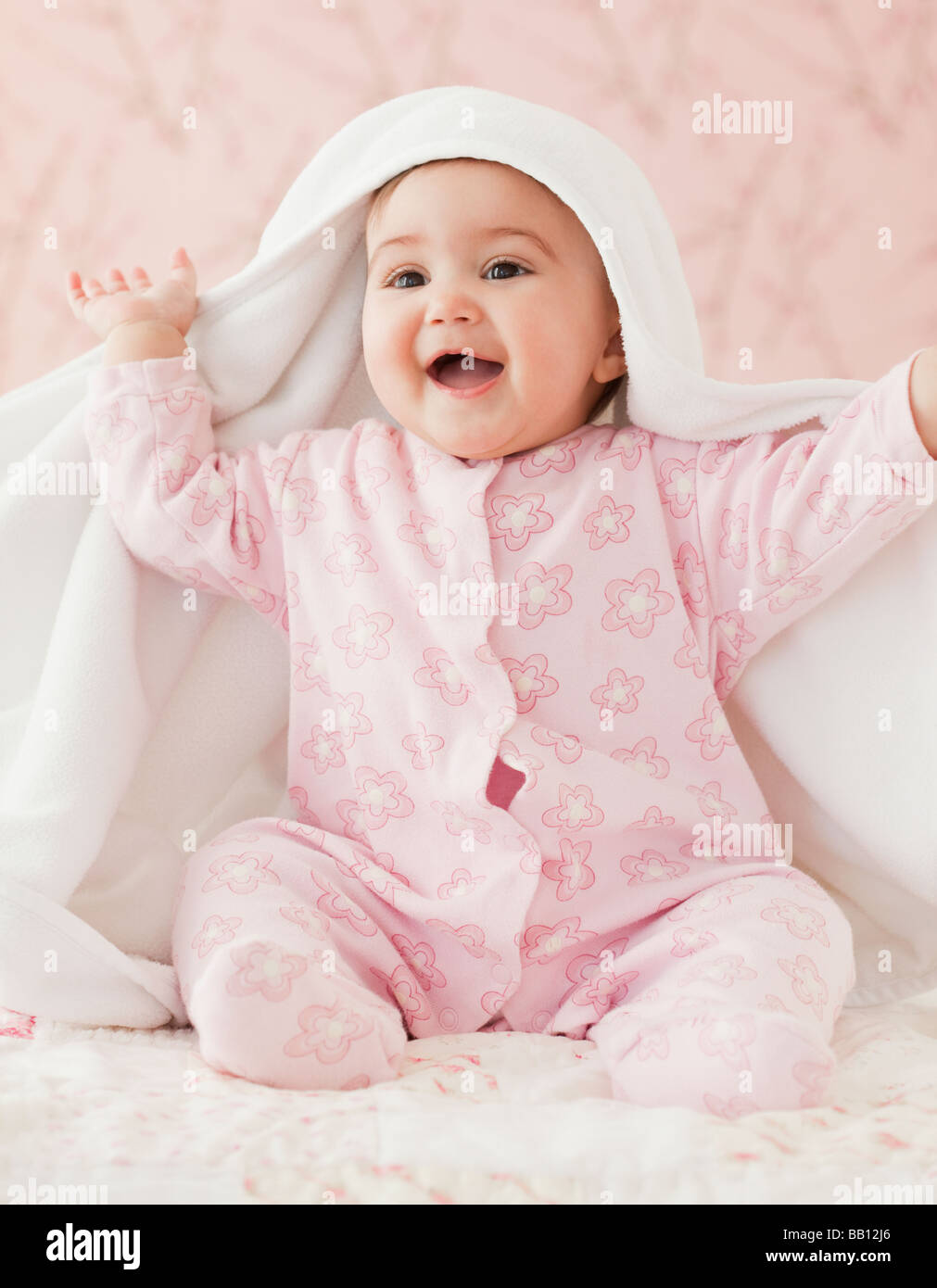 Mixed Race baby girl jouer peek-a-boo sous couverture Banque D'Images