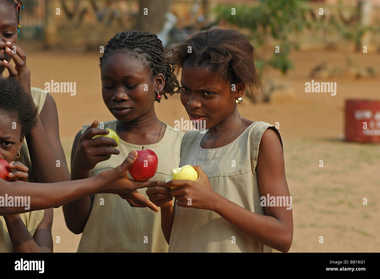 Bénin PORTO NOVO African school girls eating et l'échange des pommes rouges et vertes pour la pause Banque D'Images