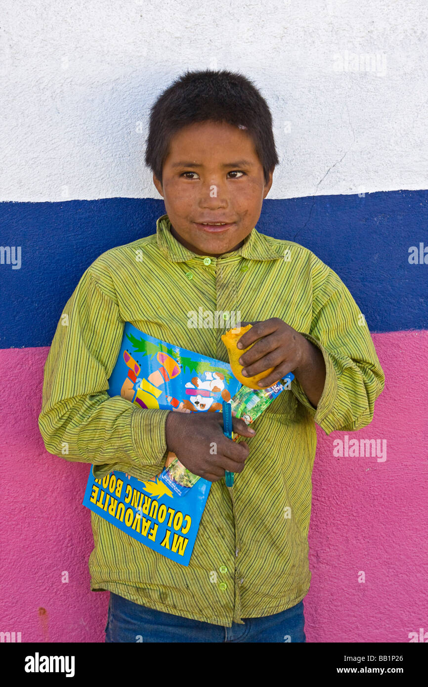 Jeune garçon à la mangue et les fournitures scolaires qu'il a reçu en cadeau dans le village de Tarahumara San Alonso Mexique Copper Canyon Banque D'Images