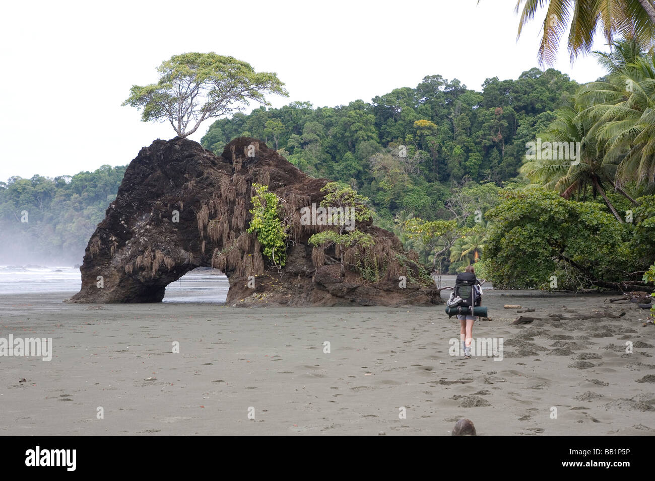 Une femme avec un sac à dos le long du littoral sablonneux fo du Parc national Corcovado, Costa Rica. Banque D'Images