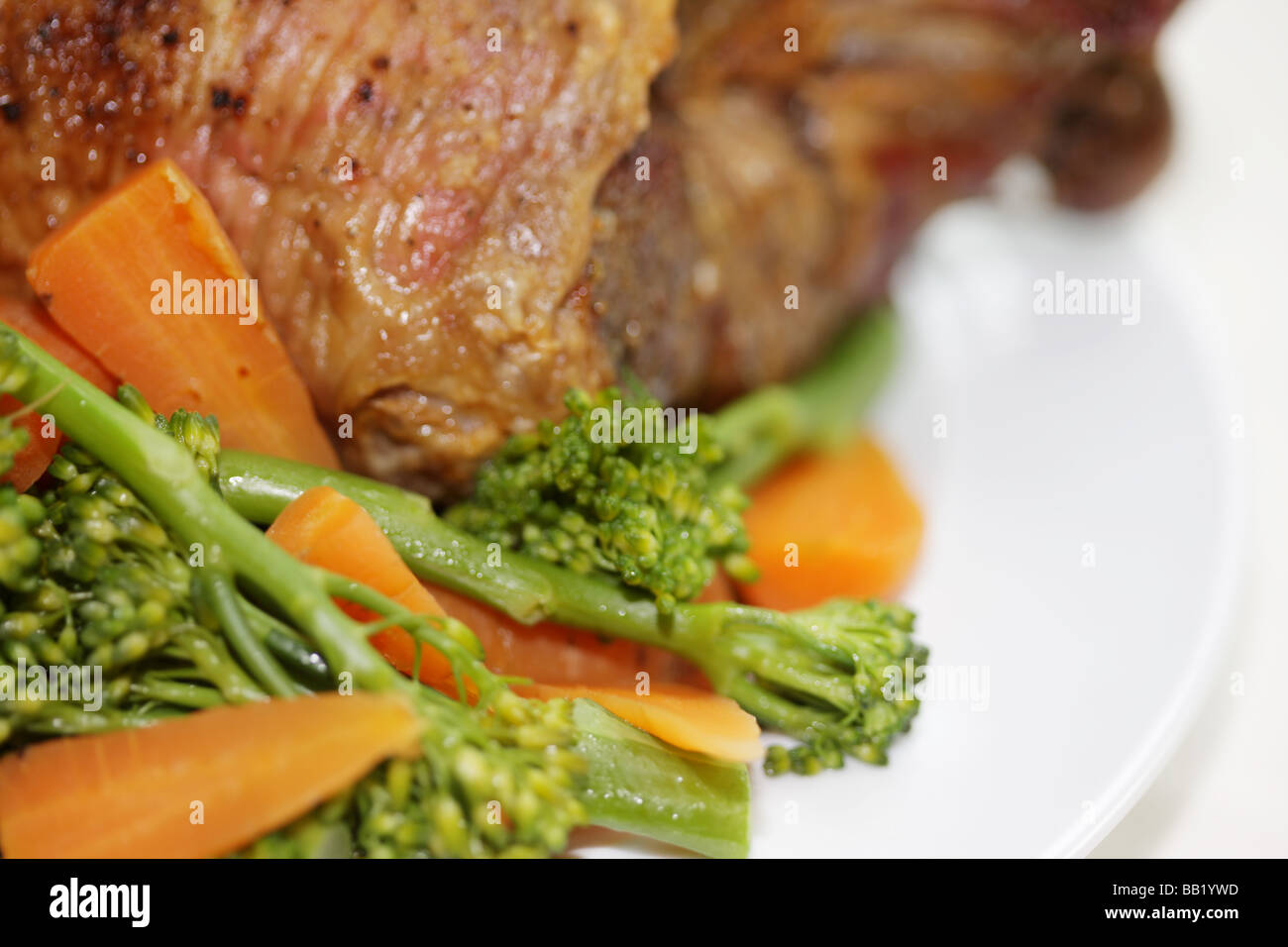 Les frais Gigot d'agneau avec des légumes y compris le brocoli et les carottes isolé sur un fond blanc avec aucun peuple Banque D'Images