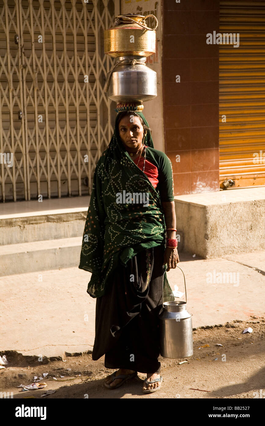 Une femme dans la région de la ville de Gujarati Rajkot, Inde. Elle porte sur sa tête des pots et dans sa main gauche. Banque D'Images