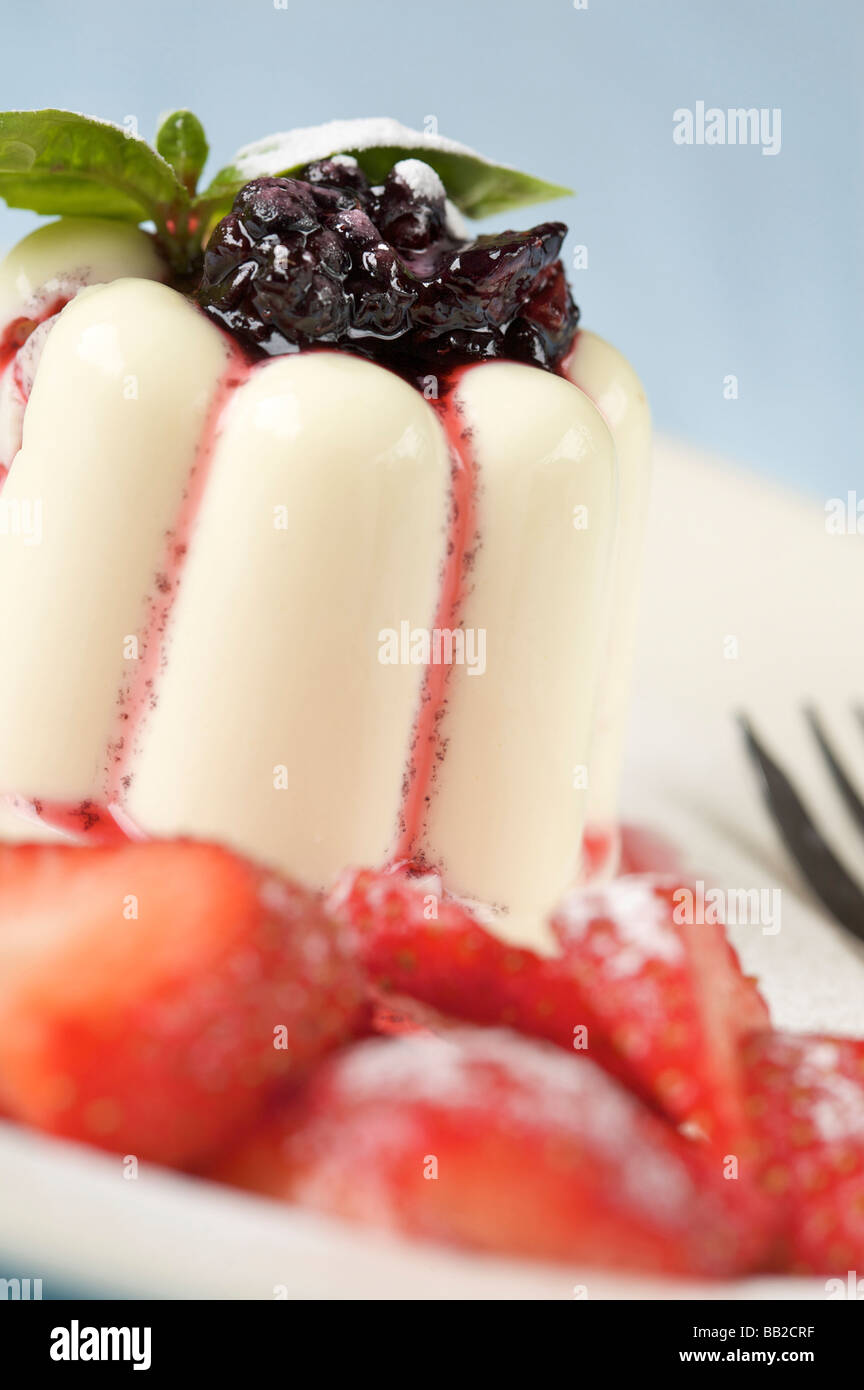 Le panna cotta dessert surmontée de black berry sauce et fraises Banque D'Images
