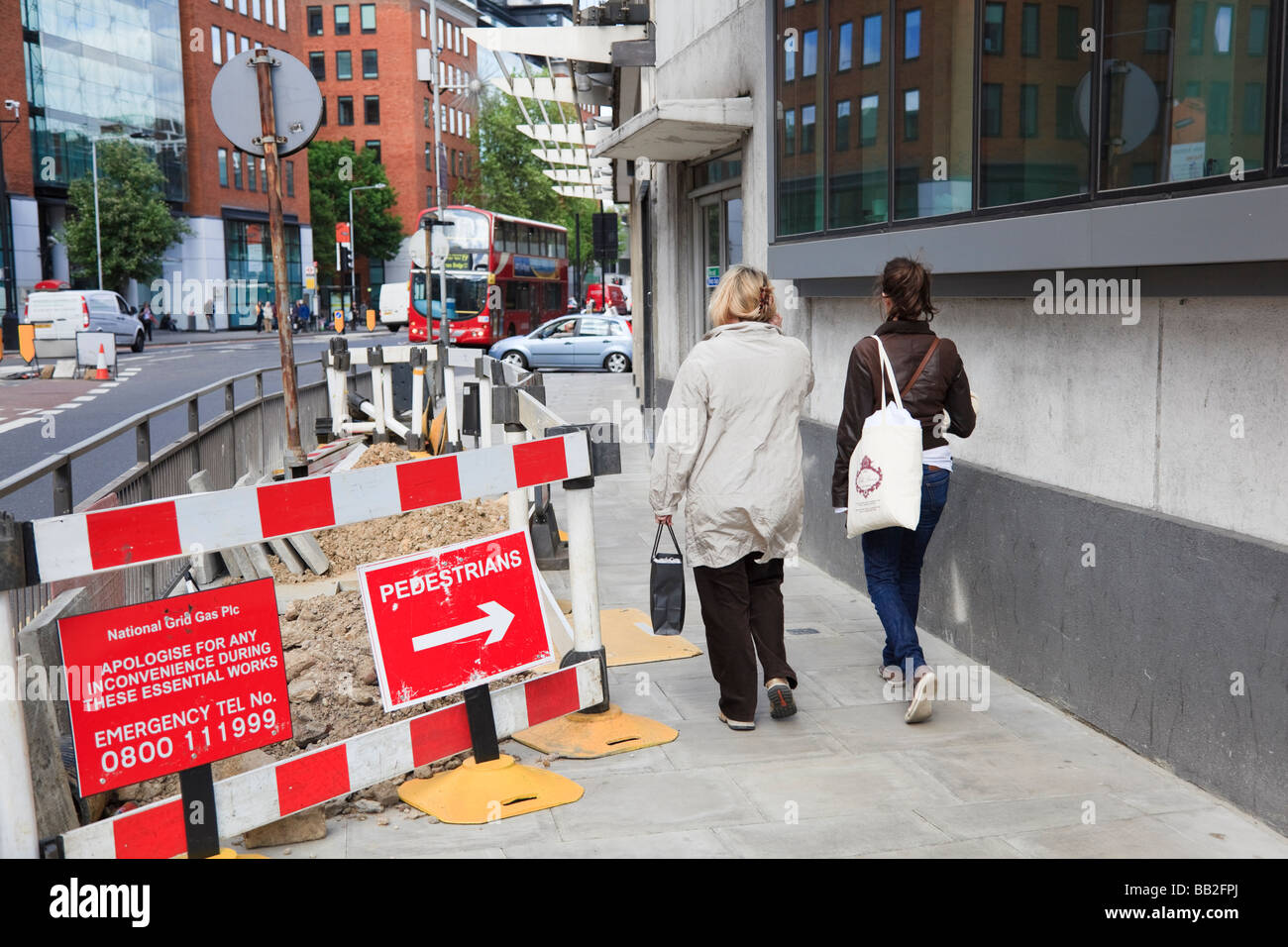Deux femmes piétons pass travaux routiers sur des panneaux de direction Drakes Street, Bloomsbury, London, UK Banque D'Images