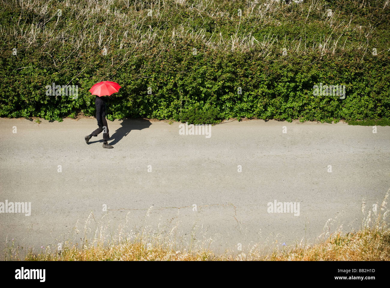 Personne marchant avec parapluie rouge Banque D'Images